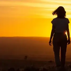 Image of woman staring out on sunset landscape